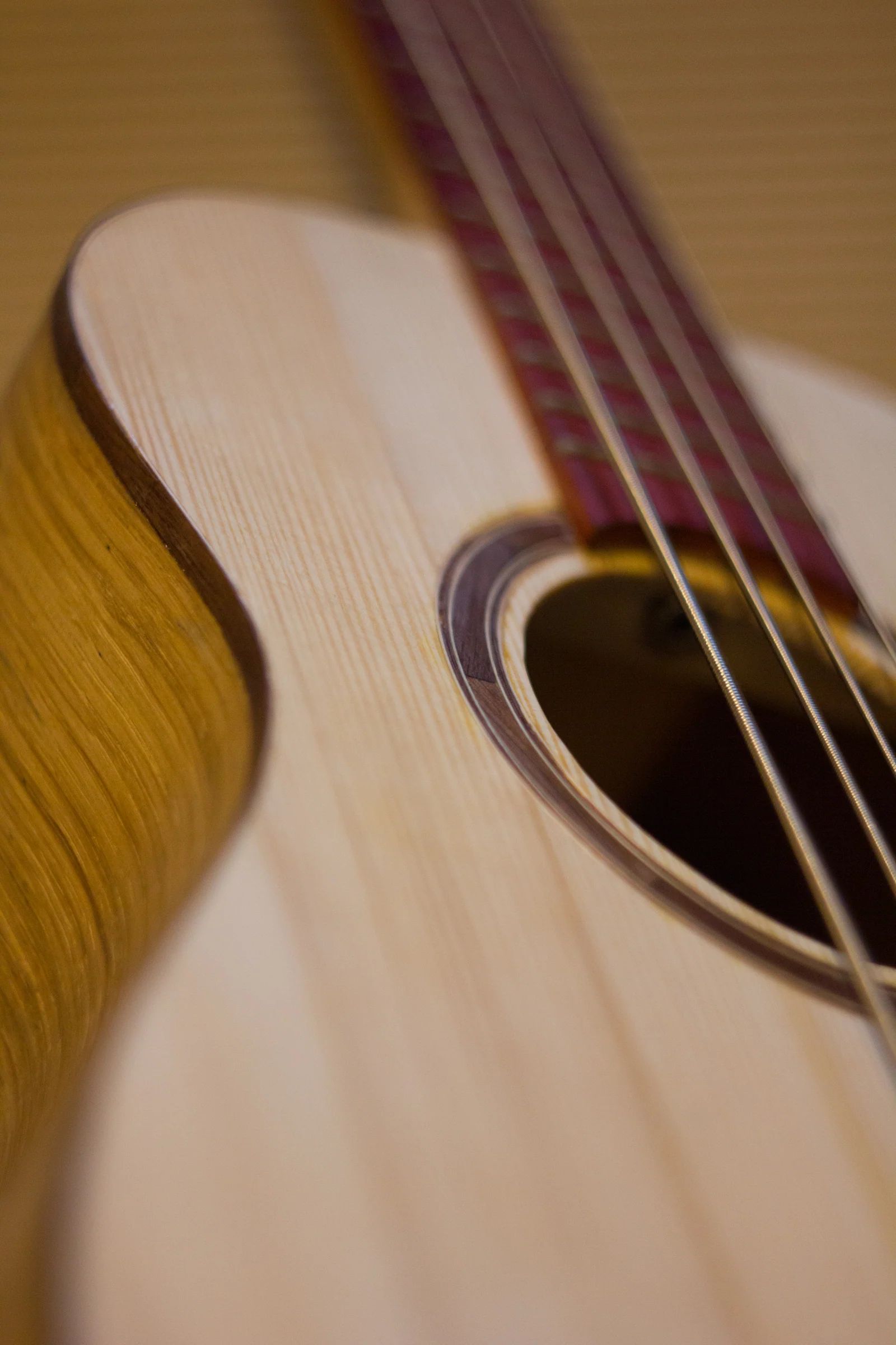 Close-up of the soundboard, strings, and sound hole of the acoustic uke-bass