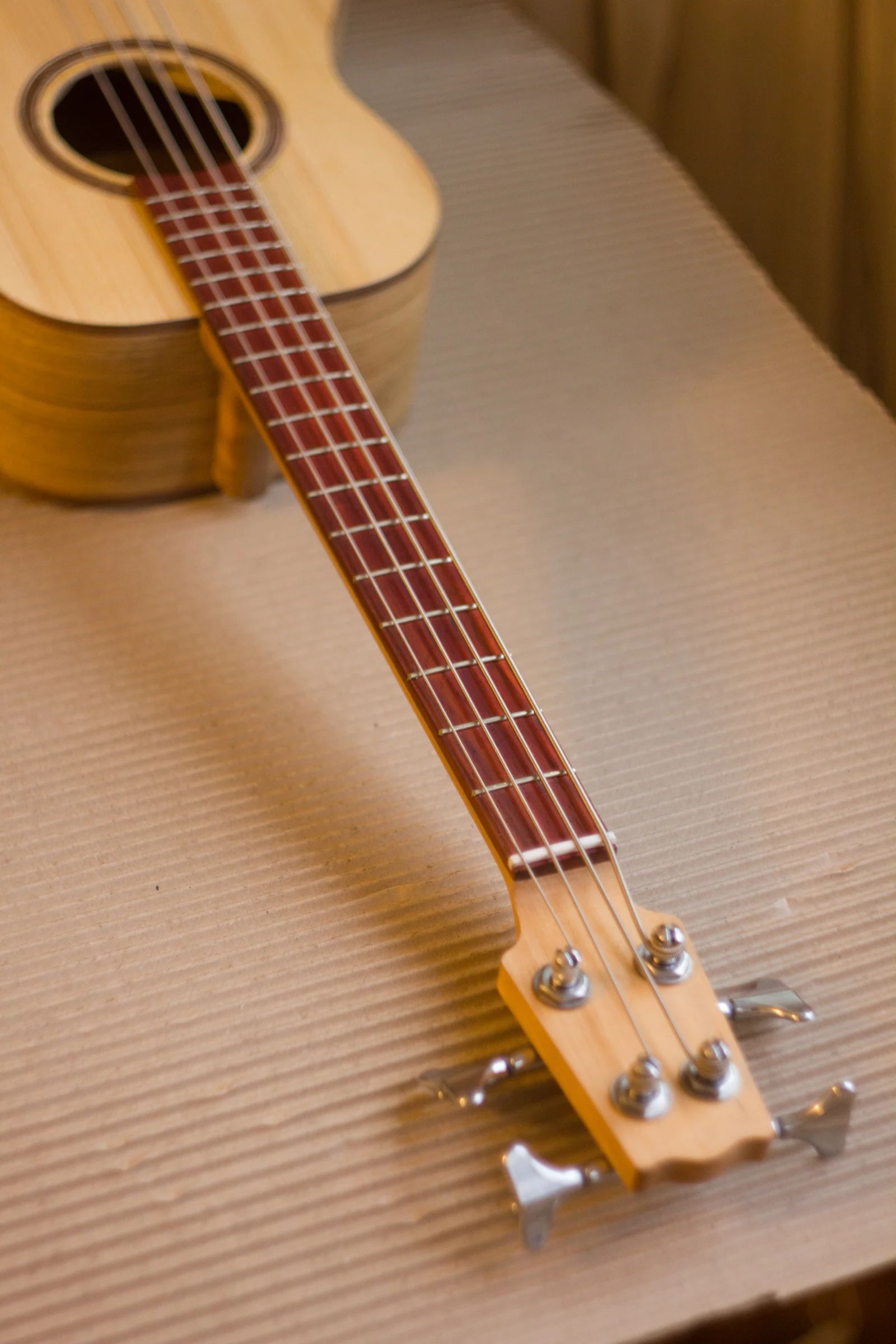 Handmade acoustic uke-bass shown with its maple neck and compact body