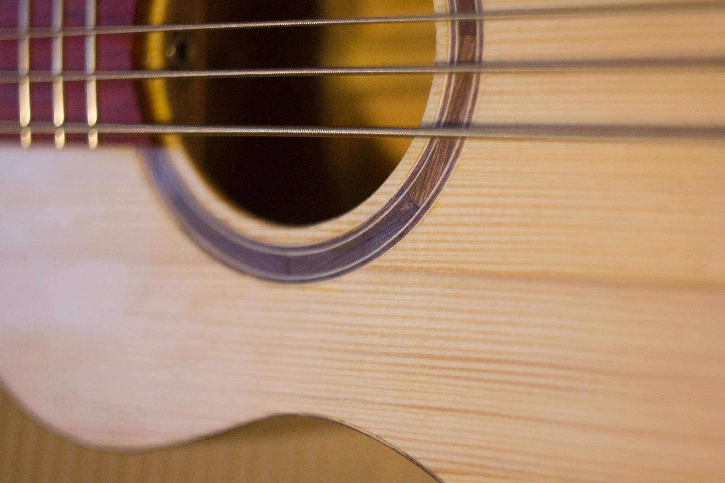 Close-up of the sound hole and strings of a handmade acoustic uke-bass