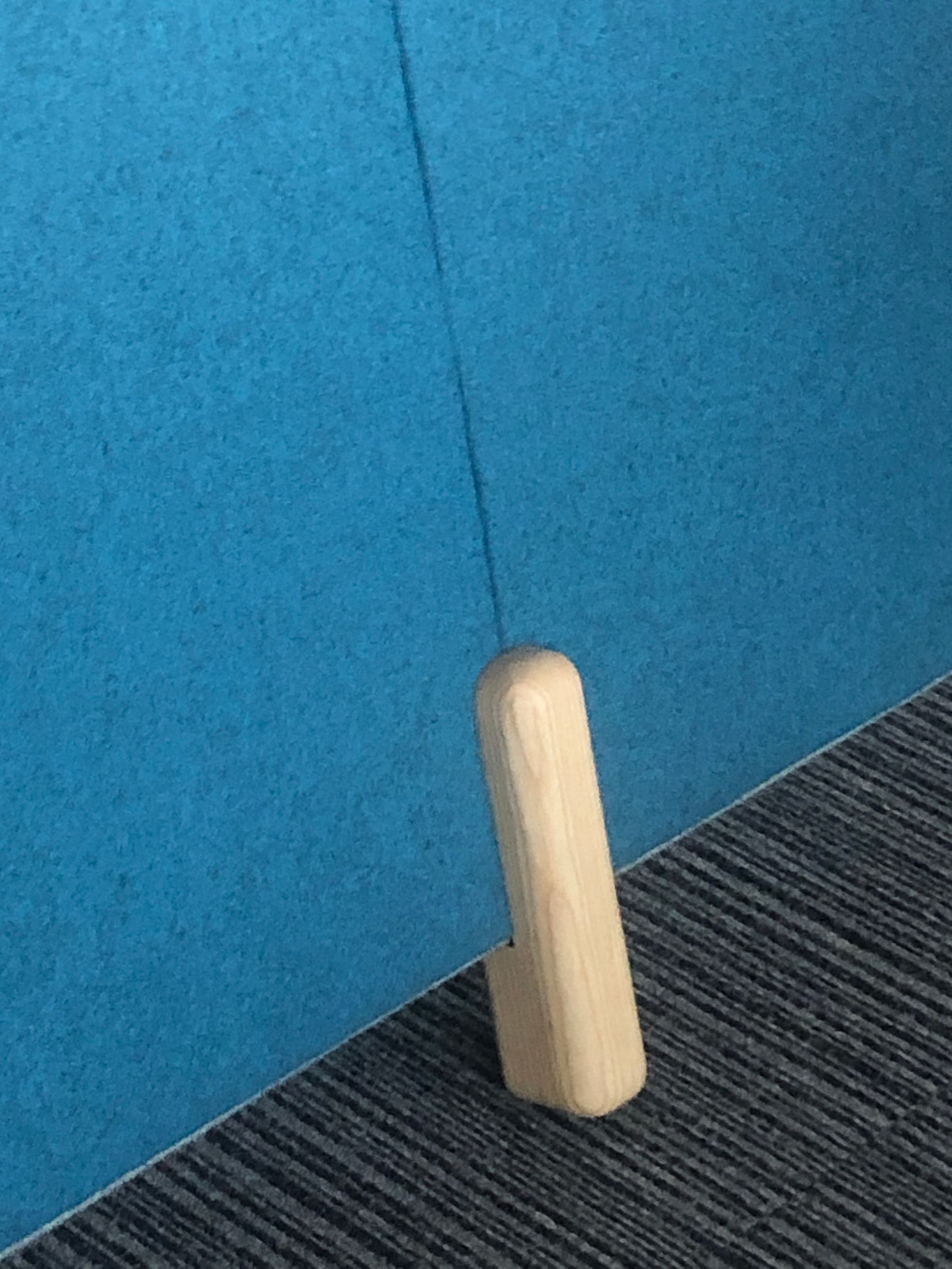 Installed prototype detail showing a timber support at the base of a blue acoustic panel