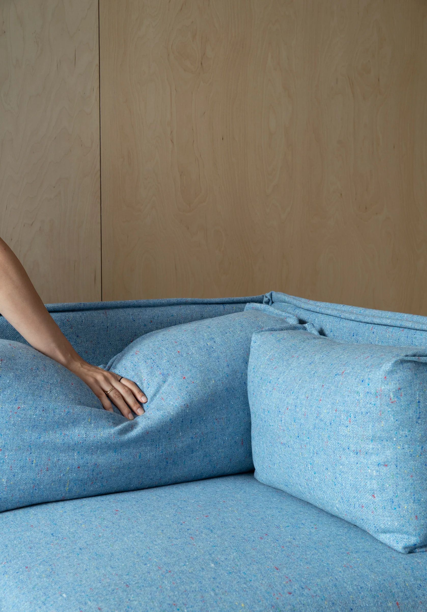 Hand pressing the blue upholstered seat cushion