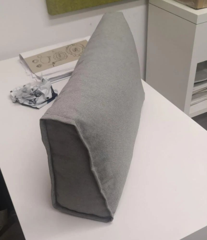 Small grey upholstered prototype cushion on a worktable