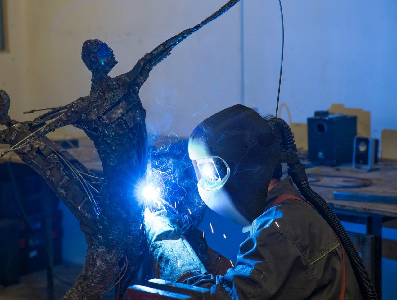 Welder using the WeldLite helmet under blue workshop light